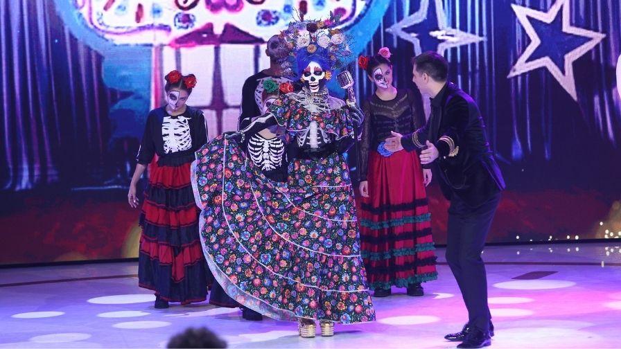 masca Femeia Schelet la Revelionul Starurilor 2022 cu dan negru inconjurata de dansatori in costume populare mexicane