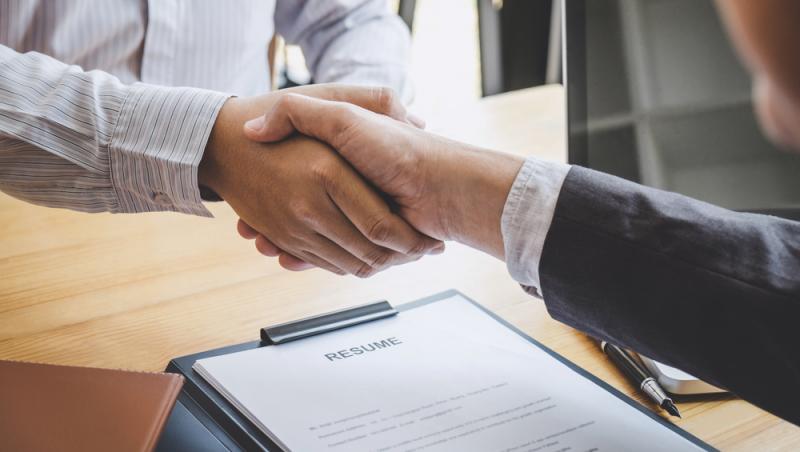 doi bărbați care își dau mâna deasupra unui cv